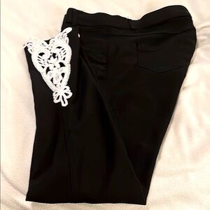 Black pants with white lace at bottom on each side.